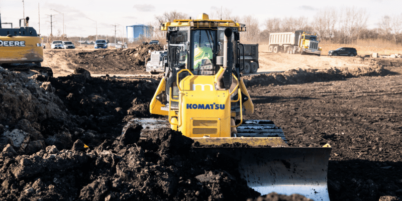 A yellow Komatsu bulldozer moves soil at construction site.